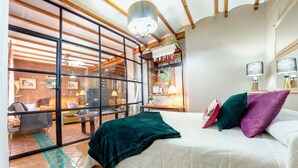 Une chambre à coucher avec un lit, un bureau et une chaise. Il y a une fenêtre donnant sur un mur de briques et un balcon.