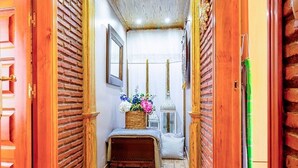 Un couloir aux murs en bois, avec un banc et une petite table agrémentée de fleurs.