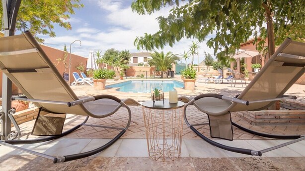 Un espace aménagé au bord de la piscine, avec des chaises longues, une petite table et une piscine.