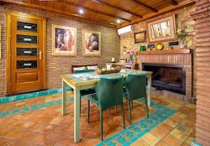 A room with a brick fireplace, a wooden door with glass panels, and a tiled floor with a blue border. - 'Villa Sierra Nevada de Pilar I' with Mountain View, Pool & Wi-Fi (Padul)