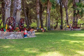 A garden with a stone wall, a statue, and decorative wheels.