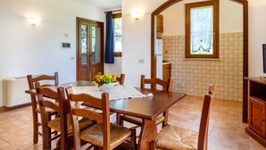 Un coin repas avec une table en bois, des chaises, un vase de fleurs et un mur recouvert de carreaux.