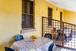 Una habitació amb una taula, cadires, una finestra i vista cap a una altra habitació separada per una partició.