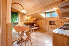 Un interno in legno con un tavolo da pranzo, sedie, un divano e un angolo cottura.