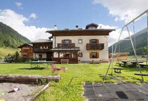Un edificio de dos pisos con un balcón, un columpio y una mesa de picnic en el patio.