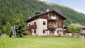 A chalet with a balcony, a wooden deck, and a mountain backdrop. - Apartment Cirmolo Chalet Cambra with Mountain View, Wi-Fi, Terrace & Garden (Livigno)