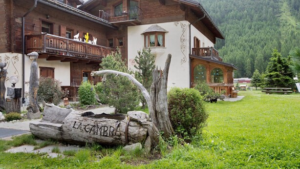 A traditional chalet with wooden balconies, a stone pathway, and a mountain backdrop. - Apartment Cirmolo Chalet Cambra with Mountain View, Wi-Fi, Terrace & Garden (Livigno)