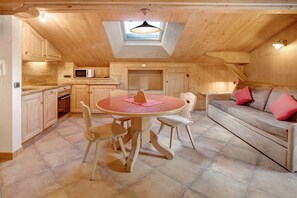 Une pièce confortable aménagée dans les combles, avec une table à manger, des chaises, un canapé et un four à micro-ondes.
