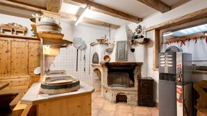 A rustic kitchen with wooden cabinets, a stone fireplace, and a modern refrigerator. - Apartment Cirmolo Chalet Cambra with Mountain View, Wi-Fi, Terrace & Garden (Livigno)