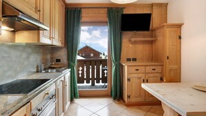A kitchen with wooden cabinets, a built-in oven, a sink, and a window with curtains. - Apartment "Larice Chalet Cambra" with Mountain View, Terrace & Garden (Livigno)