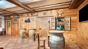 A rustic wooden interior with a bar area, wooden barrels, and shelves with bottles. - Apartment "Larice Chalet Cambra" with Mountain View, Terrace & Garden (Livigno)