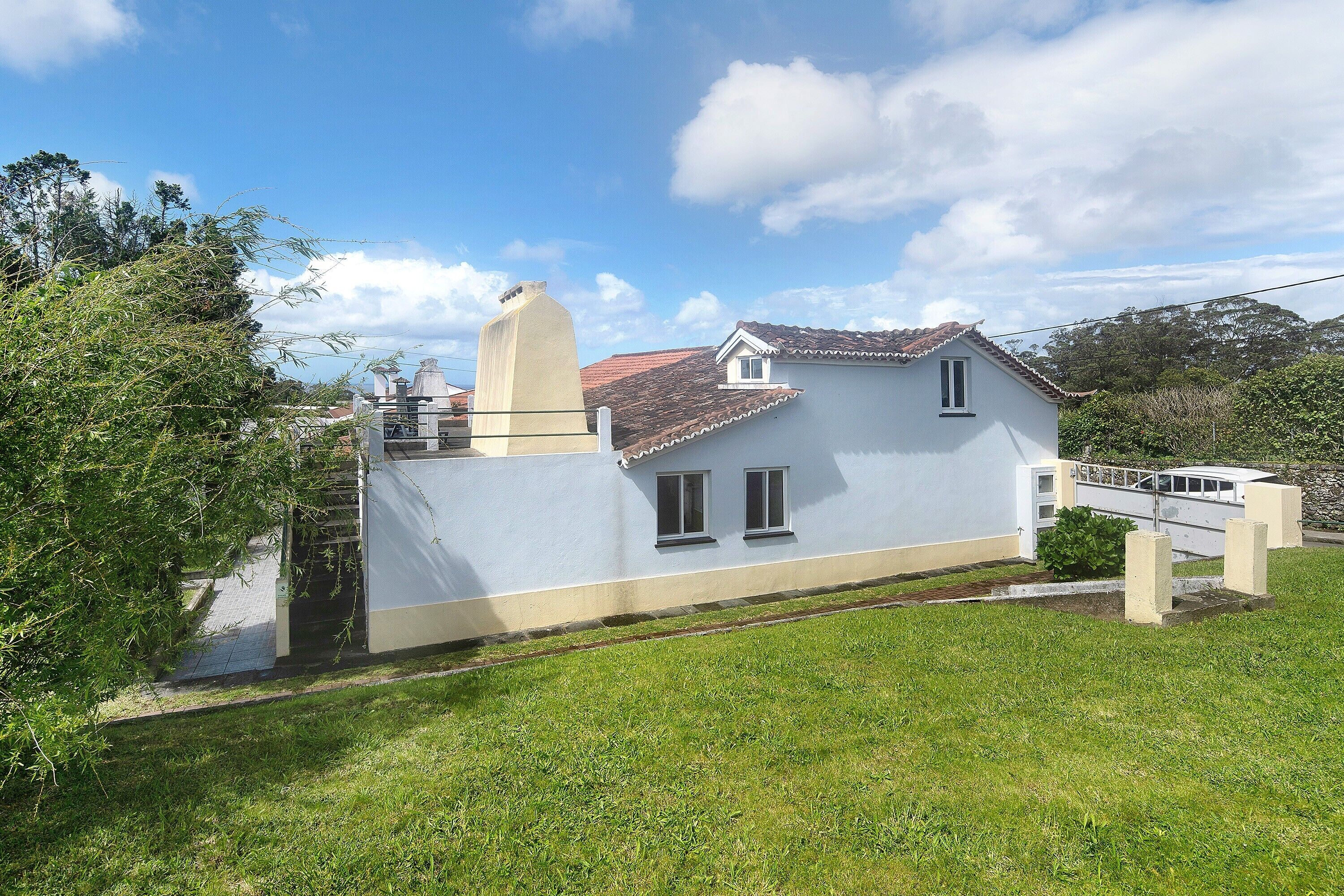 A single-story house with a tiled roof, a small attached garage, and a grassy yard.