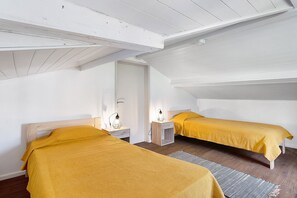 Une chambre avec deux lits, des têtes de lit en bois, des tables de chevet et un plafond avec des poutres apparentes.