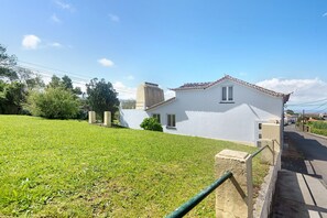 Un bâtiment blanc avec un toit en tuiles, une petite fenêtre et une structure en béton sur le côté gauche.