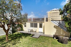 Un immeuble résidentiel doté d’un patio, d’une petite table et de chaises, et d’un arbre au premier plan.
