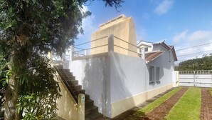 Un edificio con una escalera que lleva a una puerta, un camino de ladrillo y un árbol.