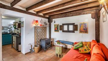 A cozy living room with a sofa, a small table, a decorative wall, and a kitchen area in the background.