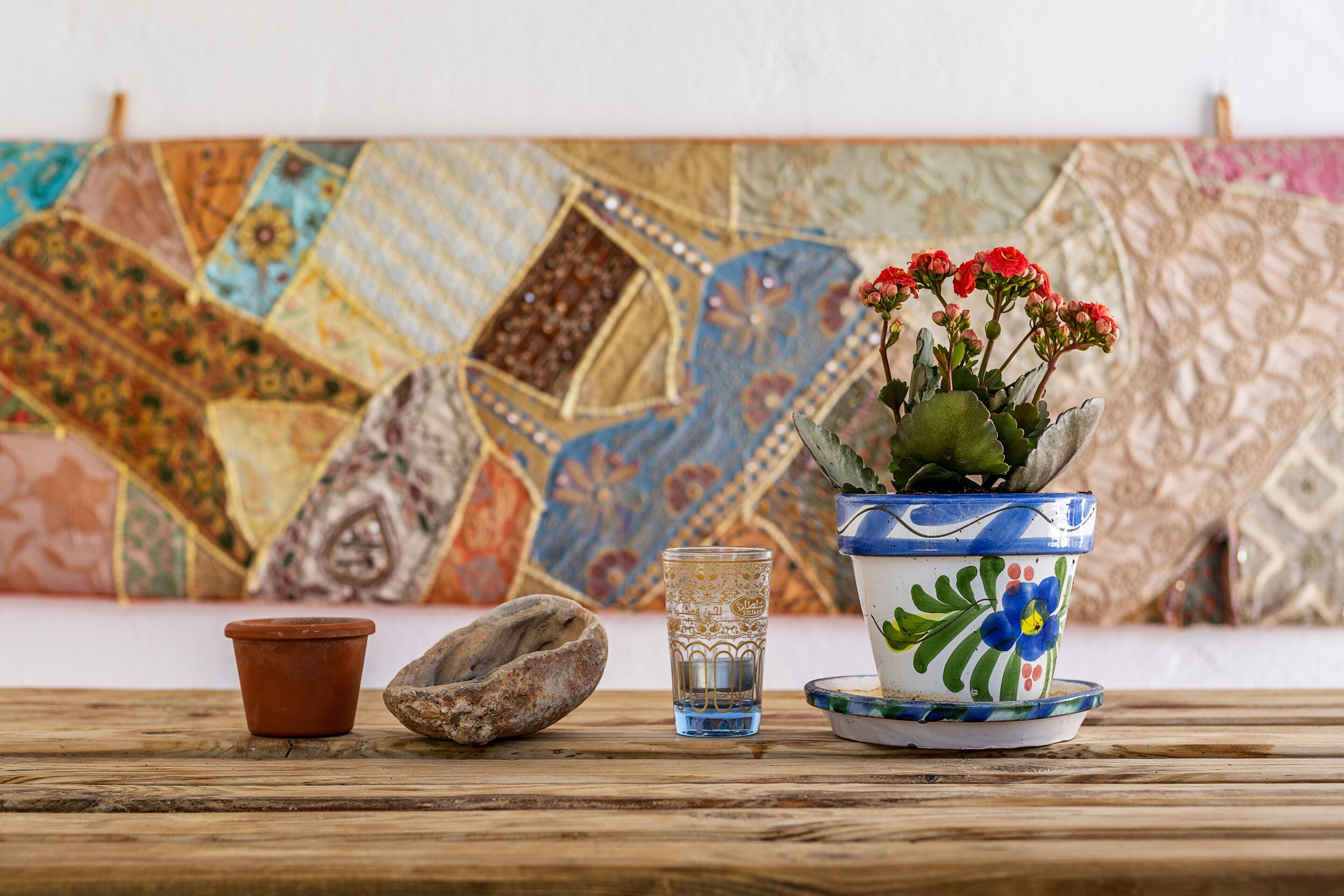 A table with a potted plant, a glass, and a stone.