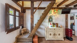 A staircase with wooden beams, a white cabinet with drawers, and a television on the wall.