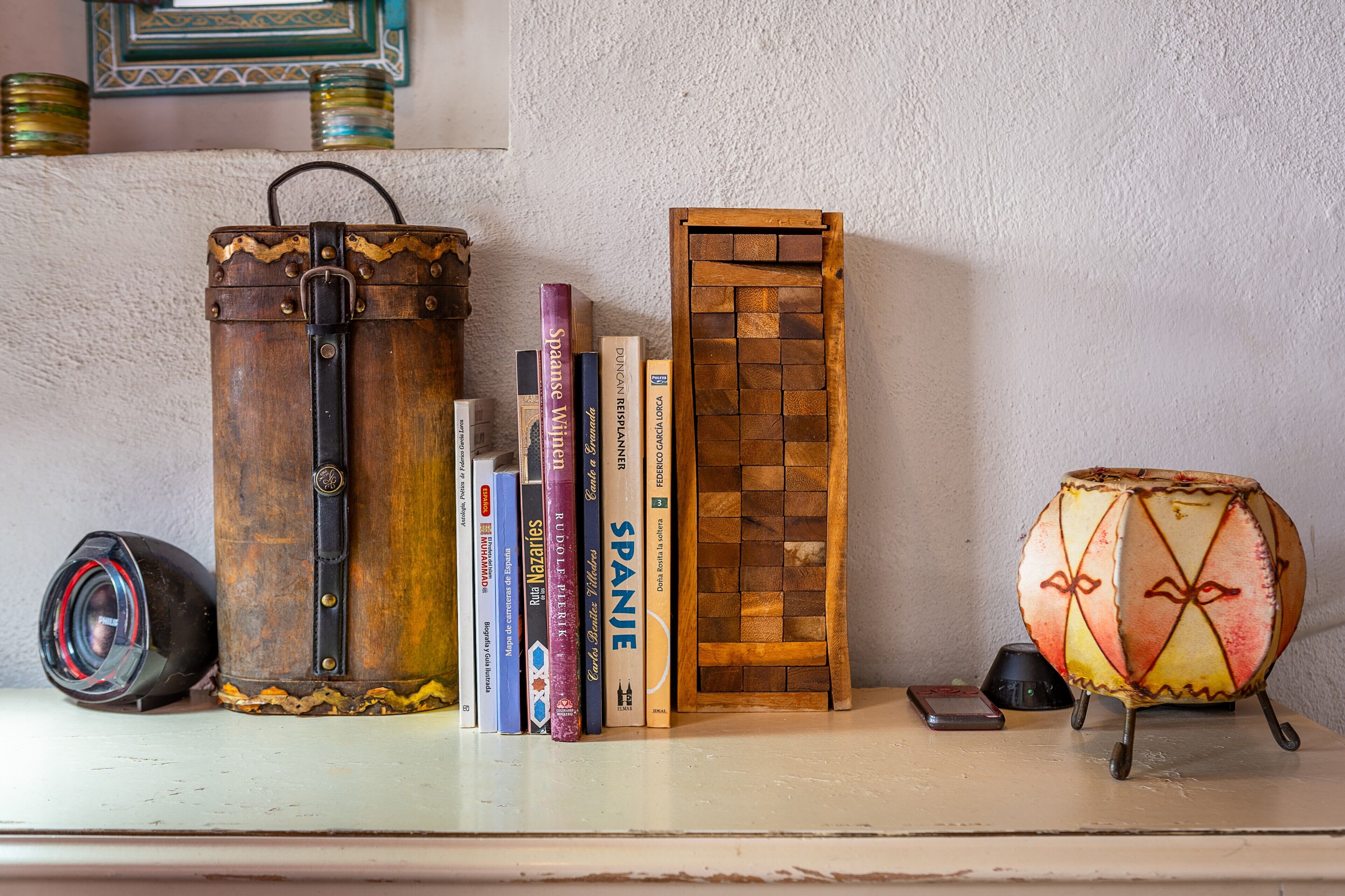 Une étagère avec des livres, un appareil photo, un tambour et une boîte en bois.