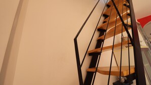 Una escalera de caracol con escalones de madera y barandillas de metal negro.