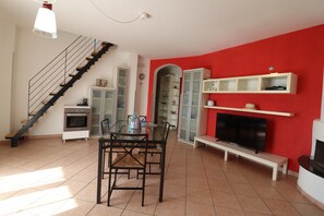 Un salon moderne avec un escalier, une table à manger et des chaises, une cheminée et des étagères intégrées.