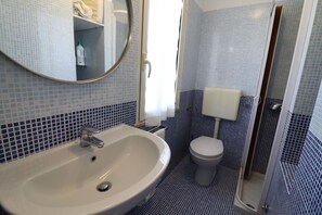 Un baño con lavamanos, inodoro y zona de ducha.