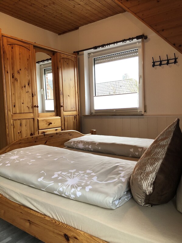 Un dormitorio con una cama de madera, una ventana con vistas y un armario de madera.