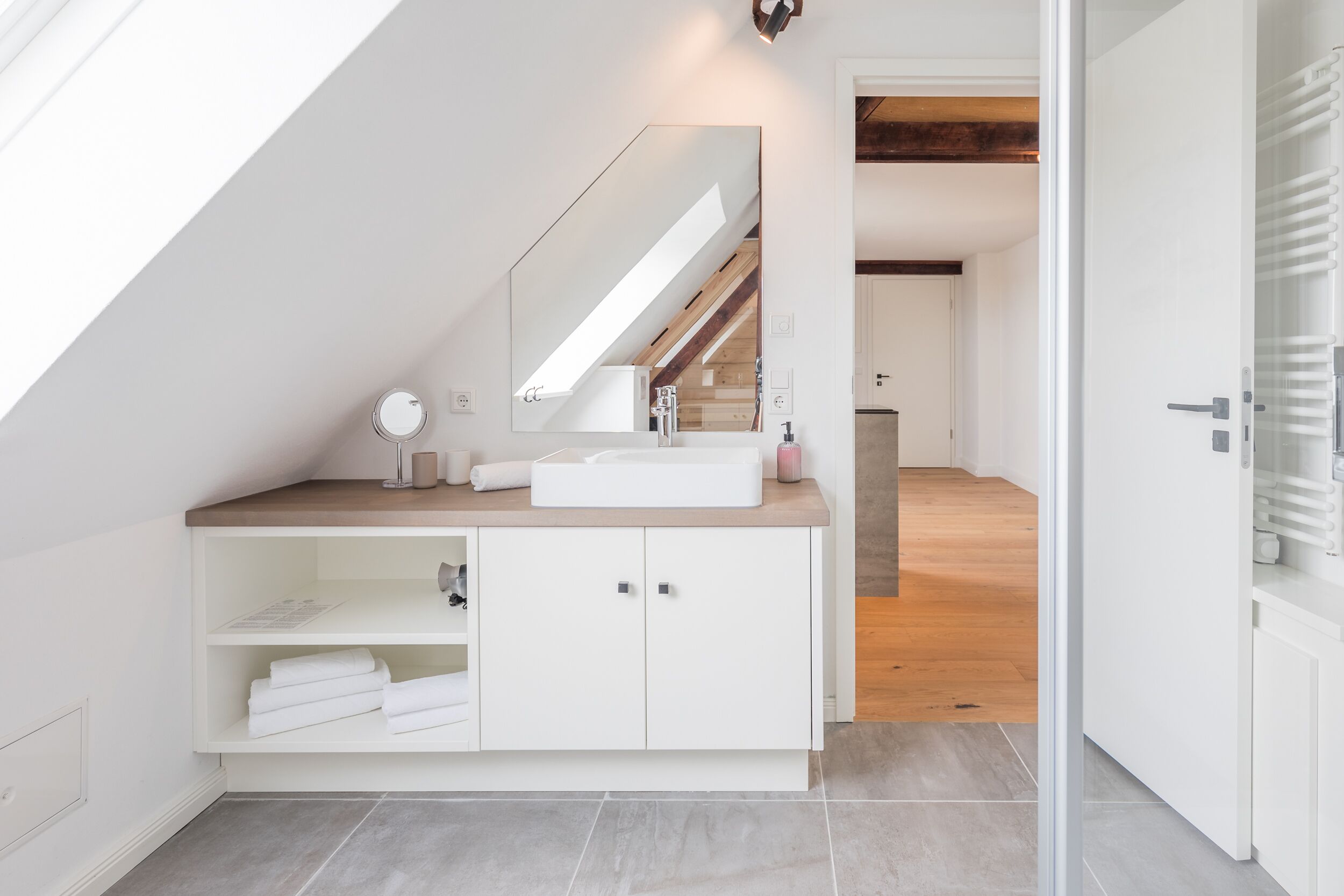 A modern bathroom with a skylight, white vanity, and a mirror.