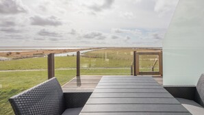 A modern outdoor seating area with a view of a distant landscape. - Vacation home Arlau Schleuse in the Hattstedtermarsch for up to 4 people (Hattstedtermarsch)