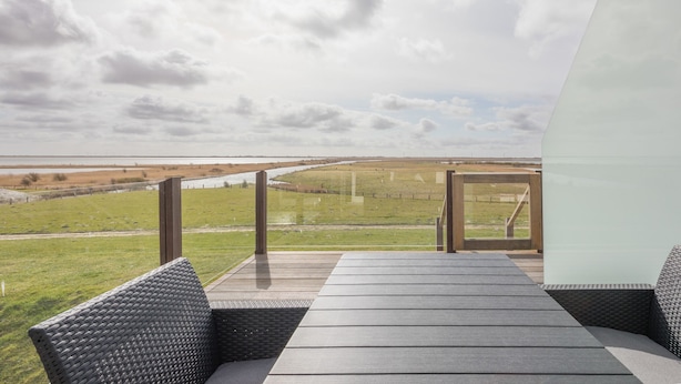 A modern outdoor seating area with a view of a distant landscape. - Vacation home Arlau Schleuse in the Hattstedtermarsch for up to 4 people (Hattstedtermarsch)