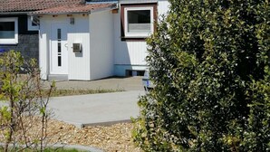 Una casa a due piani con tetto spiovente, antenna parabolica e una piccola finestra.