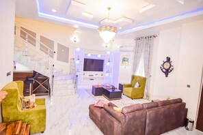 A modern living room with a staircase, a flat-screen TV, and a chandelier. - Executive 4 Bedroom House (Lekki)