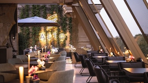 An outdoor dining area with tables and chairs, a large umbrella, and a neon sign. - The First Musica - Preferred Hotels & Resorts (Rome)