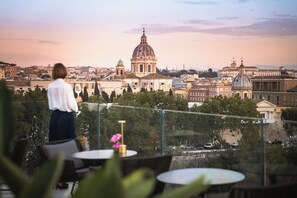 A terrace with tables and chairs overlooking a cityscape with historical buildings. - The First Musica - Preferred Hotels & Resorts (Rome)