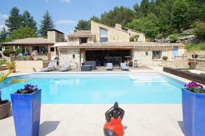 Una villa de piedra con piscina, zona de estar exterior y patio.