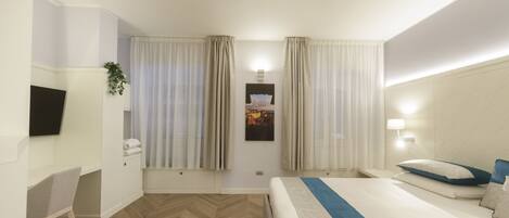A hotel room with a bed, a desk, a TV, and a window with curtains.