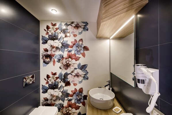 A modern bathroom with a floral wall mural, a round sink, and a hairdryer.
