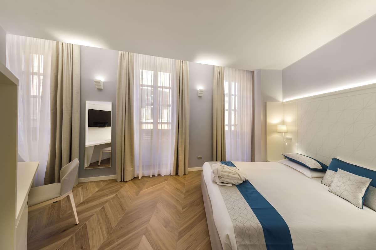 A hotel room with a bed, a desk, and a chair.