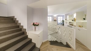 Una escalera que lleva a un rellano con un armario blanco y un florero.
