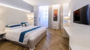 Una habitación de hotel moderna con una cama grande, televisor, escritorio y una silla.