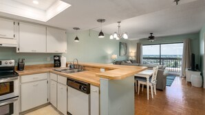 Cocina compacta con lavavajillas, un lavabo y horno empotrado. Hay un comedor con mesa y sillas, y un balcón con vistas.