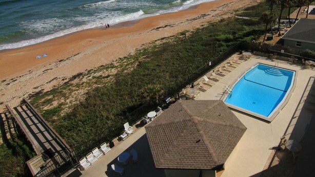 Vista de una playa con piscina y sillas de descanso.
