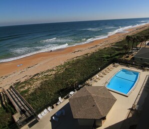 A beach view with a swimming pool and lounge chairs. - Sunset and river view condo with a large balcony and heated beachfront pool (Ormond Beach)