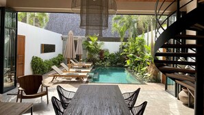 A modern outdoor pool area with lounge chairs, a wooden table, and a staircase. - Luxury 2BR Private Loft Canggu w/ Staff (Canggu)