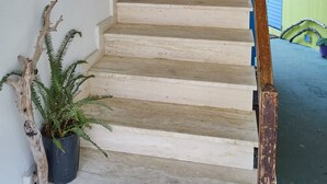 Eine Treppe mit weißen Stufen, einem Holzgeländer und Blumentöpfen.