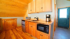 A compact kitchen with wooden cabinets, a sink, a coffee maker, a dishwasher, and a microwave.