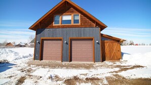 A two-story wooden building with two garage doors and a sloped roof.