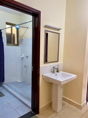 A bathroom with a shower, a sink, and a mirror.