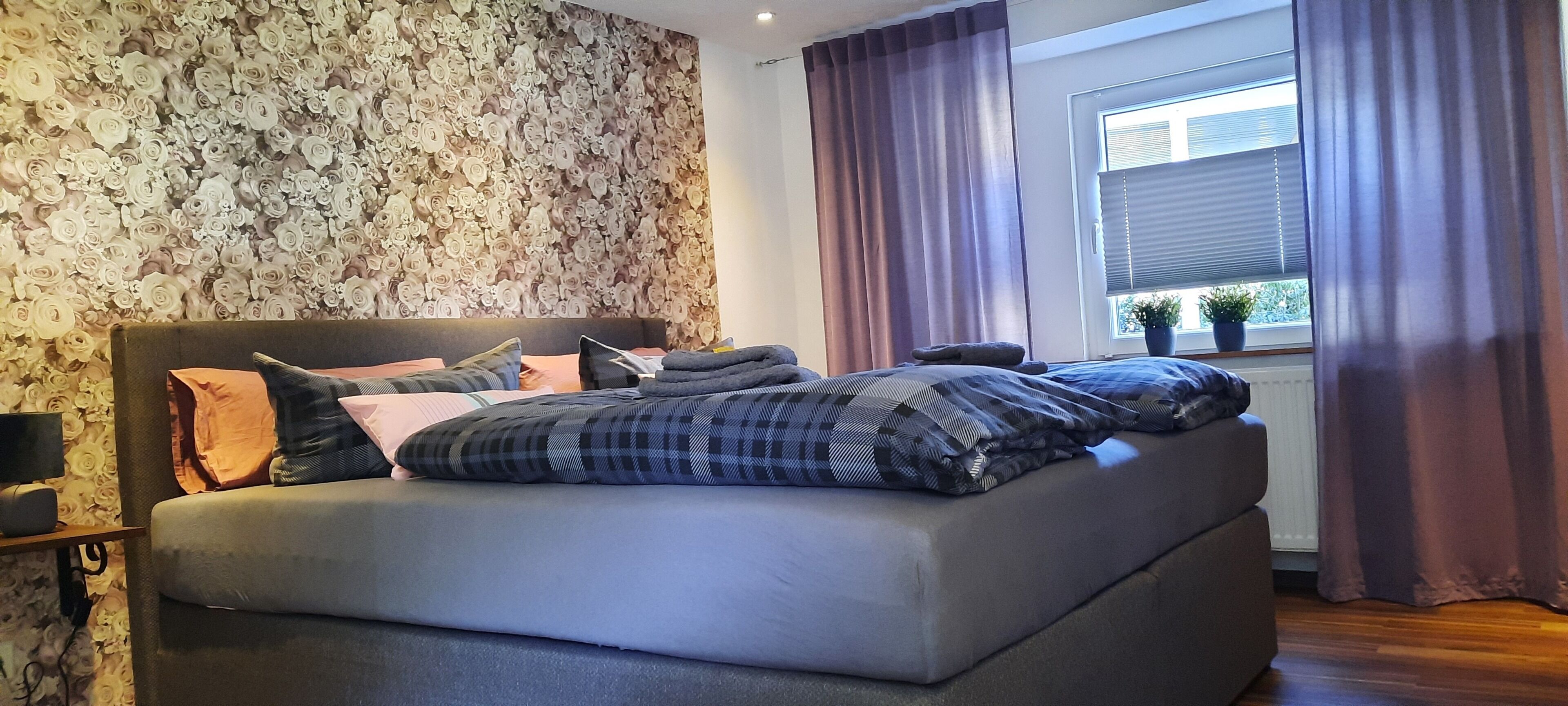 A modern bedroom with a large bed, a stone wall, and a window with curtains.